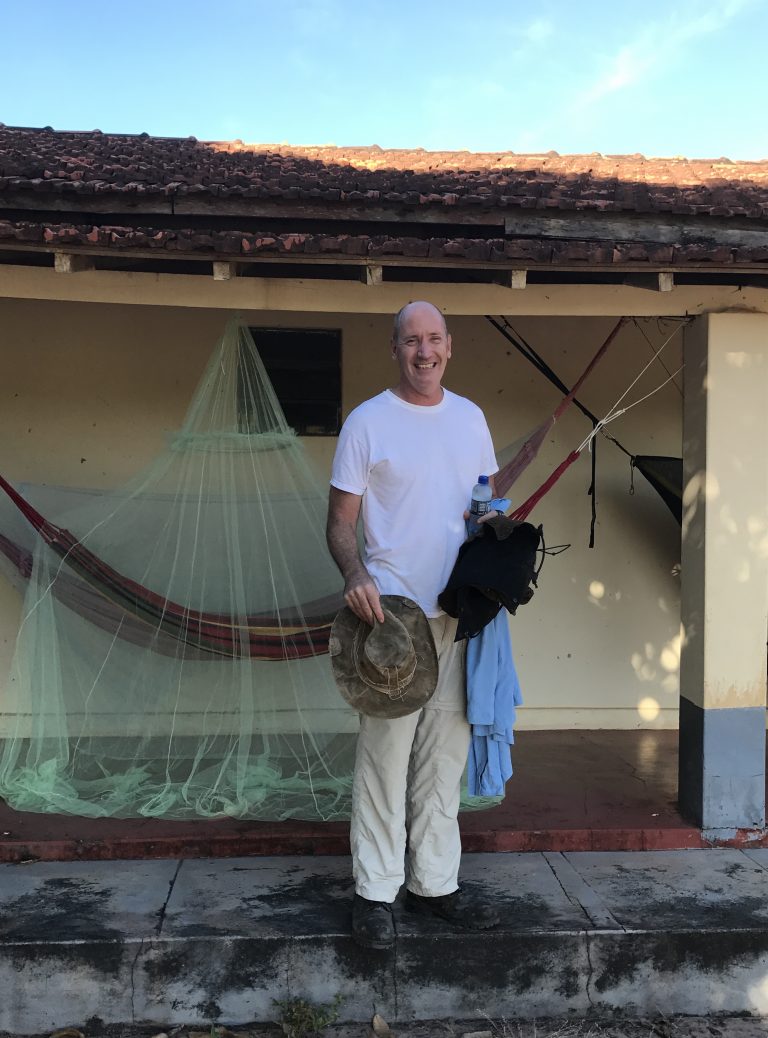 Dr. Mike Coe in front of a hammock and mosquito netting