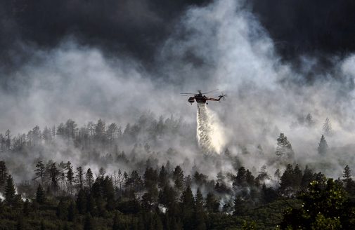 Stock image of helicopter dropping water on a forest fire.