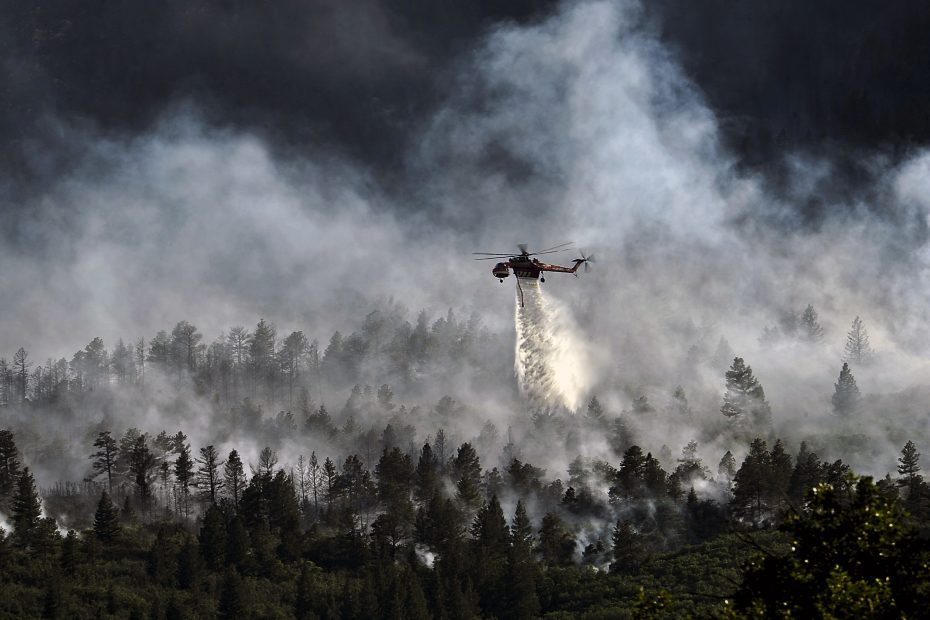 Stock image of helicopter dropping water on a forest fire.