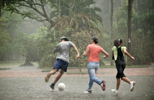 teenagers playing soccer in the rain in a park in Brazil