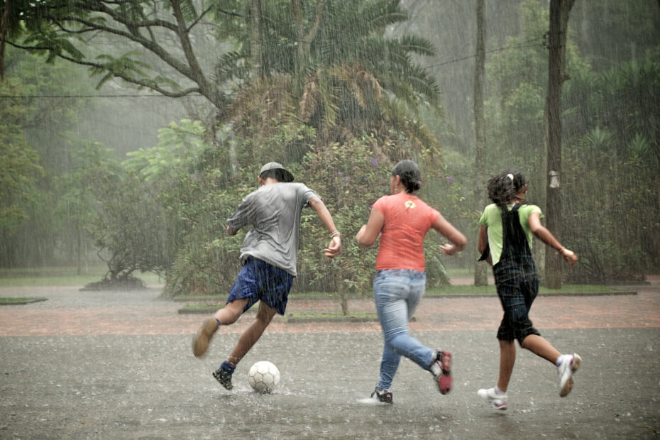 teenagers playing soccer in the rain in a park in Brazil