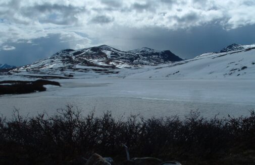 A snowy Arctic mountain with grey clouds overhead