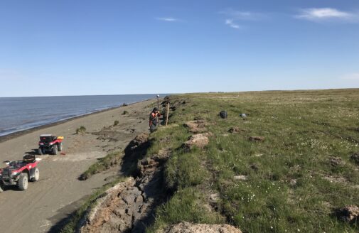 A researcher takes a measurement on a shoreline eroding due to permafrost thaw