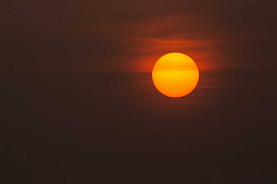 An orange sun in a dark, hazy sky over Gandhinagar, Gujarat, India