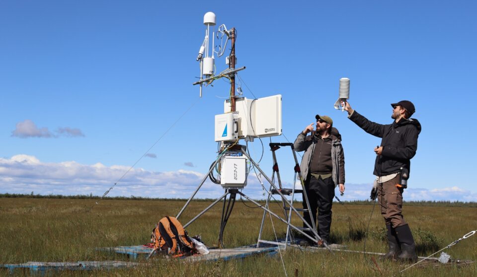 Two researchers installing an eddy covariance flux tower