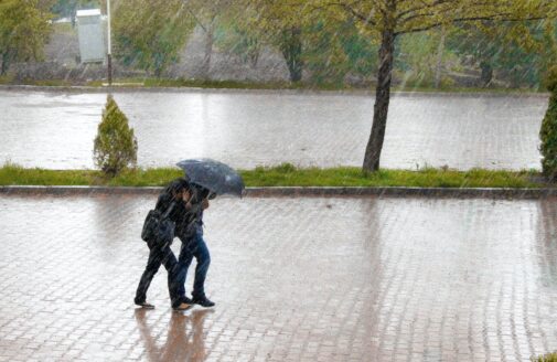 Two people walking with an umbrella in heavy rain