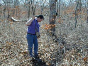 A man uses a tool to take a soil sample in the woods