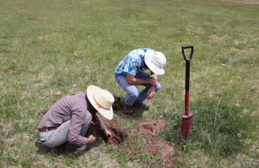 jon sanderman and megan machmuller examining a hole dug on a grassland pasture