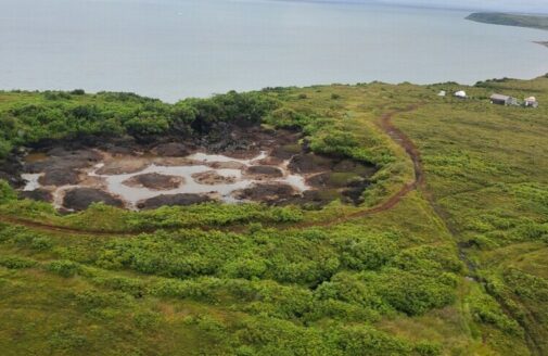 aerial photo of an empty lake bed near a larger bay surrounded by low shrubs and grass