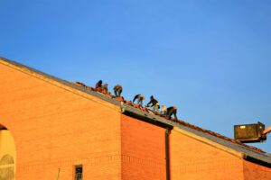 Men work on a roof in the hot sun