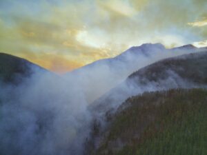 smoke hangs over a forested valley