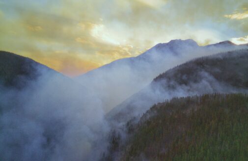 smoke hangs over a forested valley