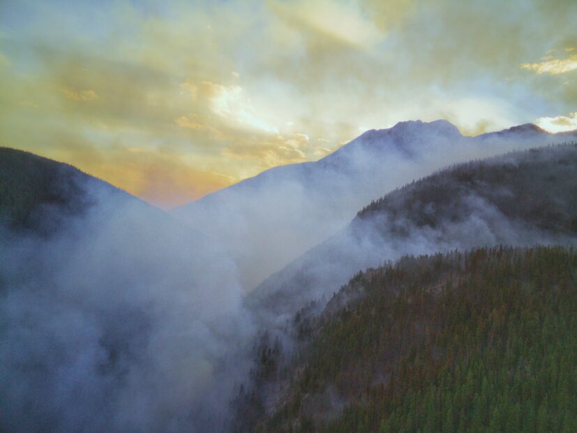 smoke hangs over a forested valley