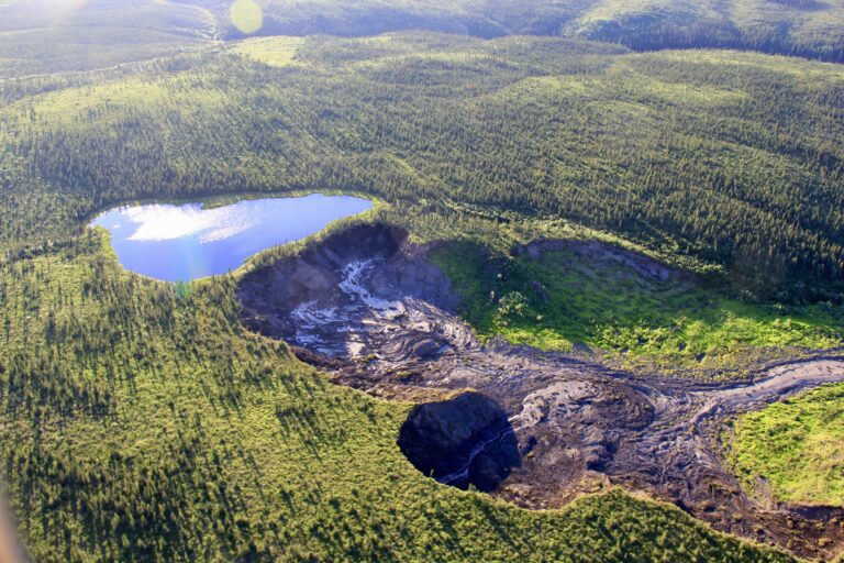 An aerial photo of a retrogressive thaw slump showing a precarious lake and the land that has sloughed away downhill of it