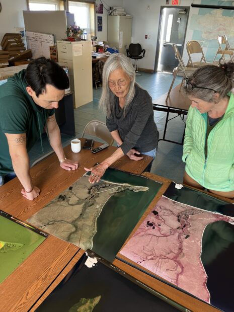 Three people looking and pointing at a map on a table