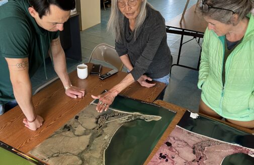 Three people looking and pointing at a map on a table