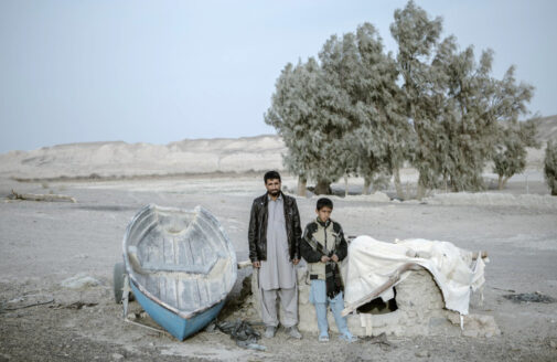 Father and son standing next to row boat in dusty, dry landscape