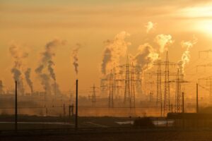 Smokestacks release plumes of exhaust into an orange sky