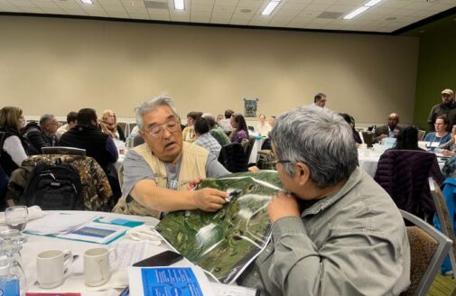 Kwethluk elders point out elements of a map in a conference hall