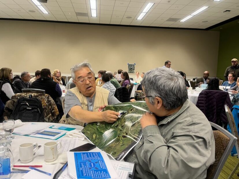 Kwethluk elders point out elements of a map in a conference hall