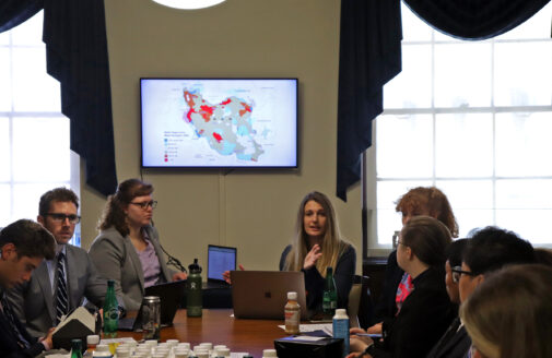 scientists in front of a presentation screen showing Iran