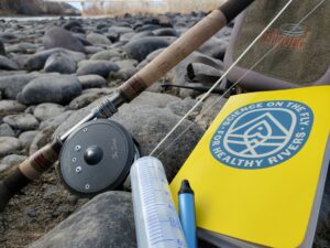 fishing rod next to water sampling equipment and a yellow notebook with the Science on the Fly logo