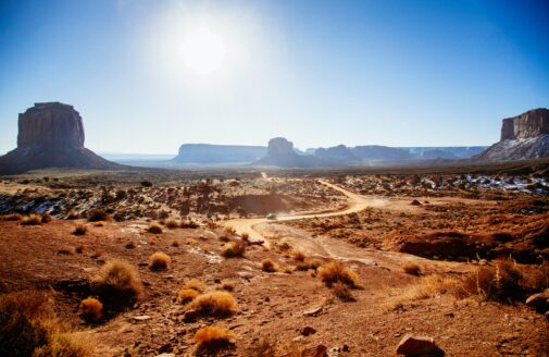 A truck drives on a road on a sunny day in Arizona's Monument Valley