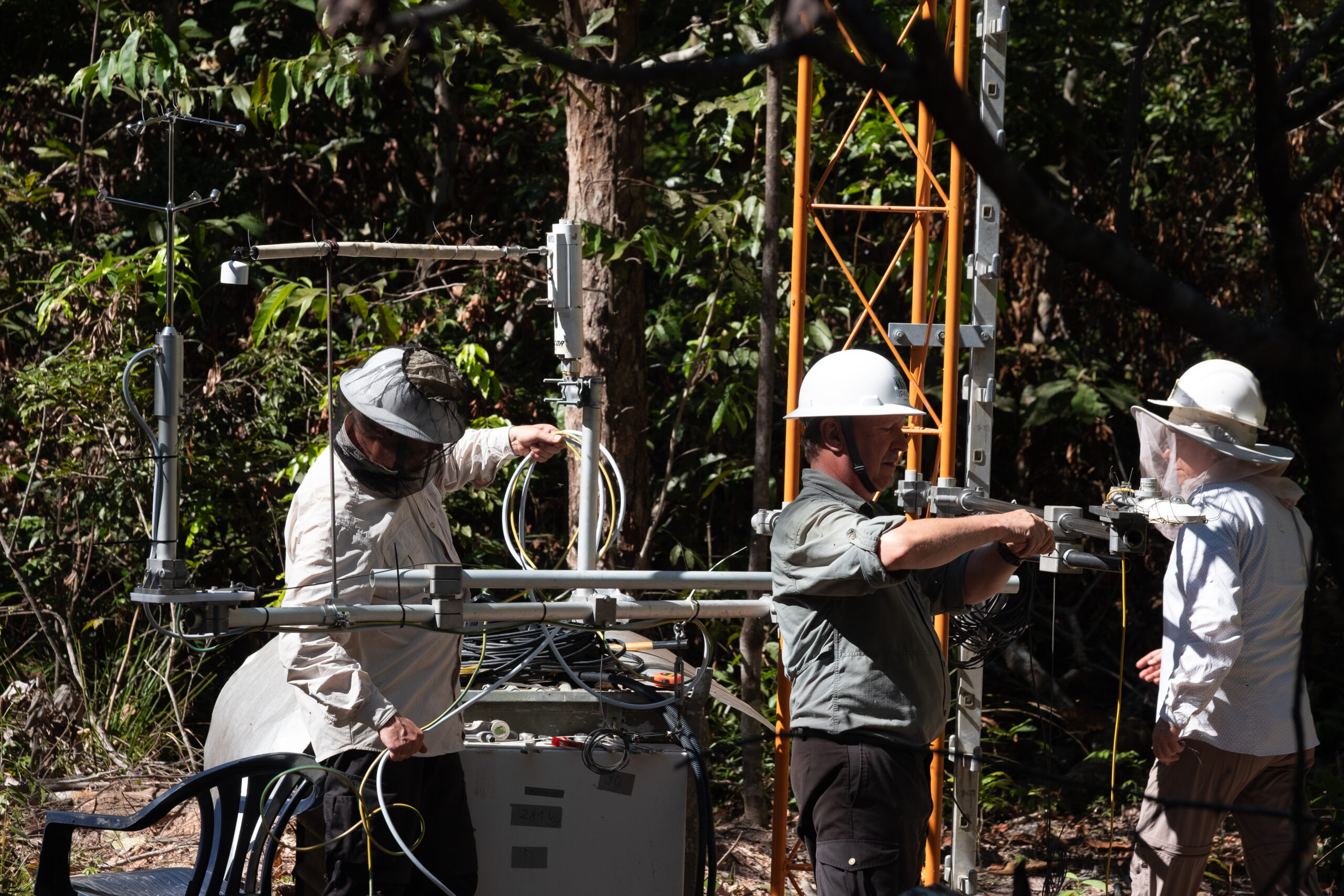 Researchers in hard hats work on towers that hold sensors and other monitoring equipment