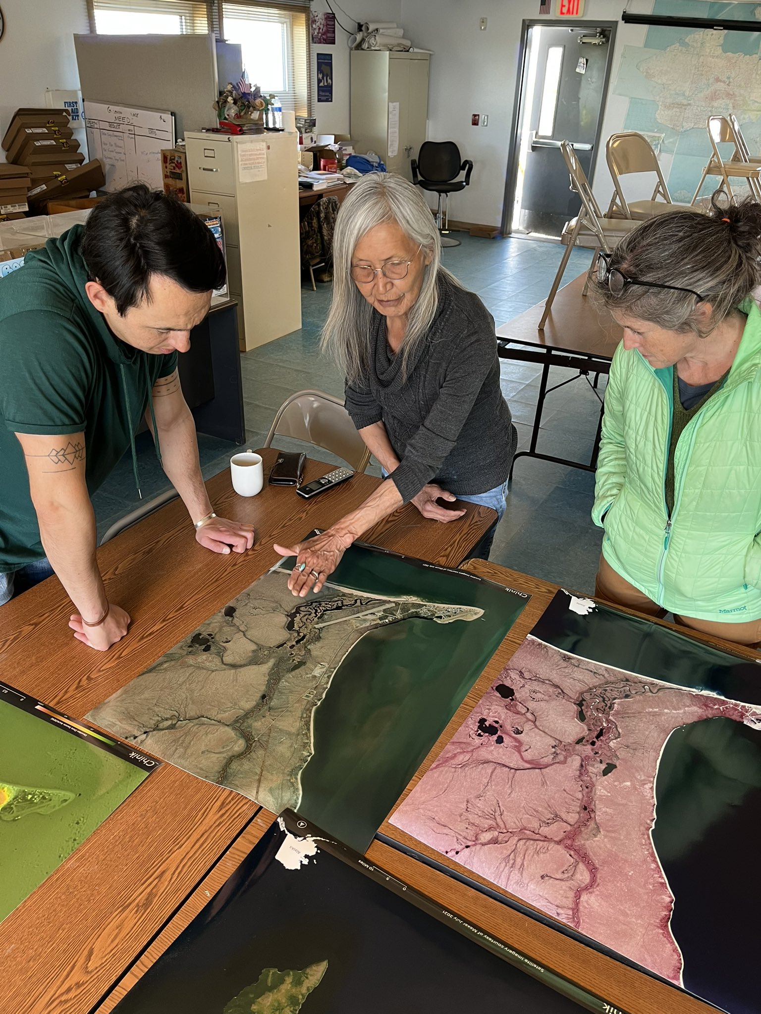 sue natali talks to Golovin community members with maps on the table