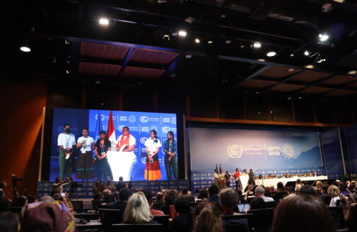 Presenters stand on a stage in front of an audience at COP27