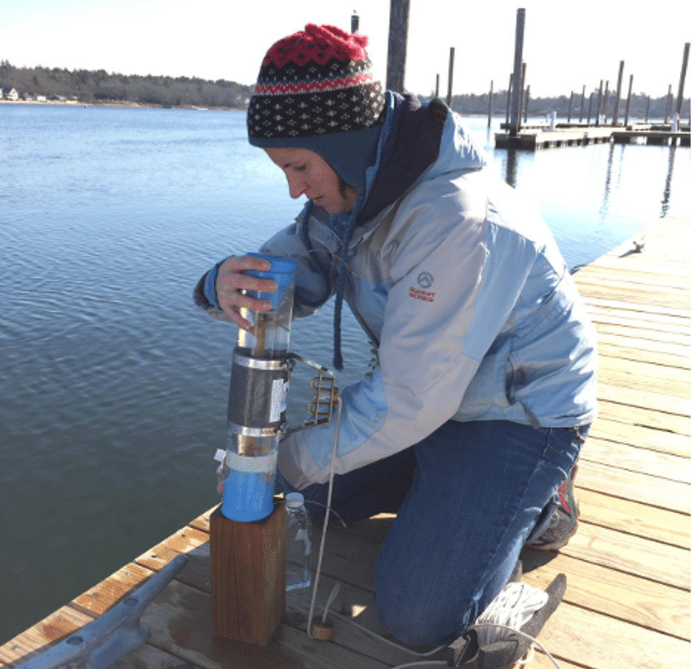 a woman works with a plastic tube full of water, inserting it into a wooden block with a hole