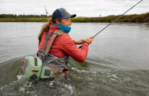 Allie Cunningham standing in a river up to her waist with a fishing rod