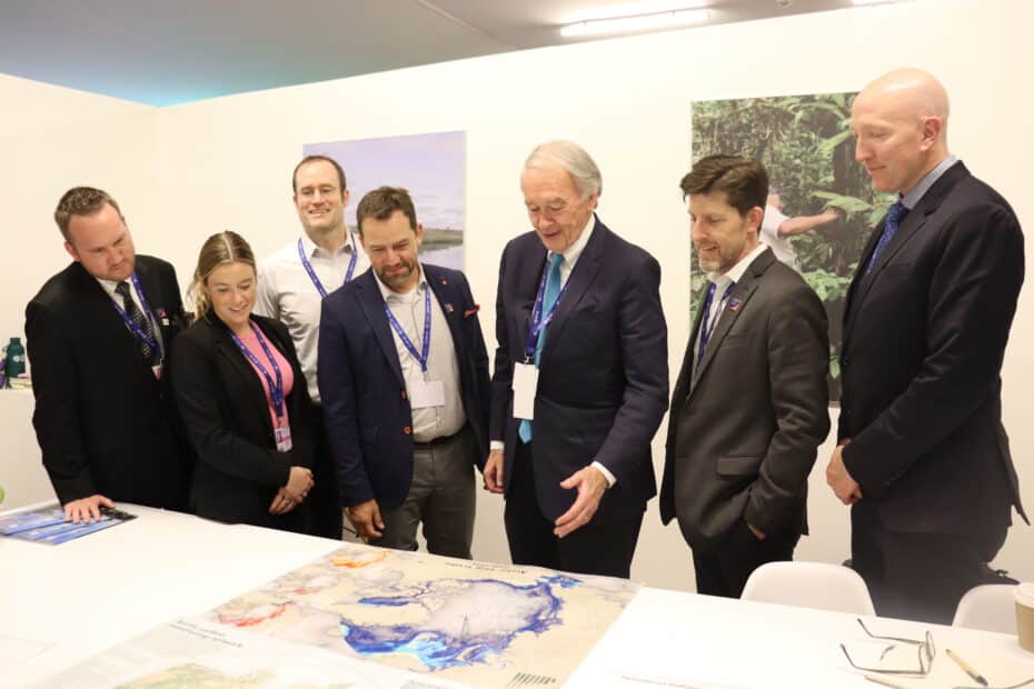 Senator Ed Markey looks at a map on a table with various Woodwell Climate staff