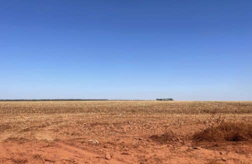 a bright blue sky over orange soil of a barren field