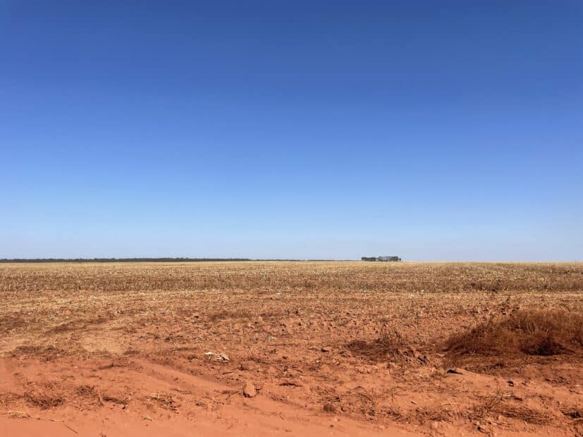 a bright blue sky over orange soil of a barren field