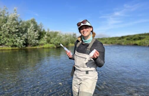 andrea norton standing in a river holding water sampling equipment