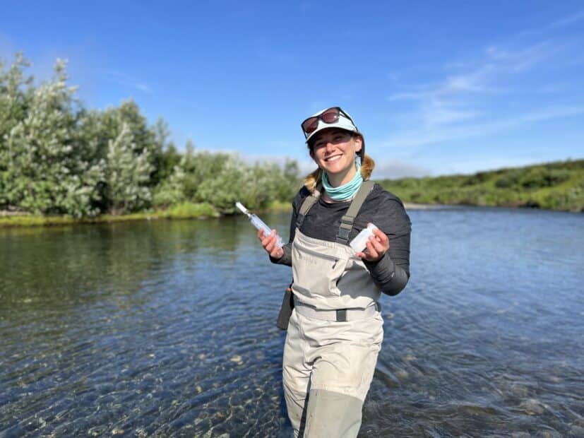 andrea norton standing in a river holding water sampling equipment