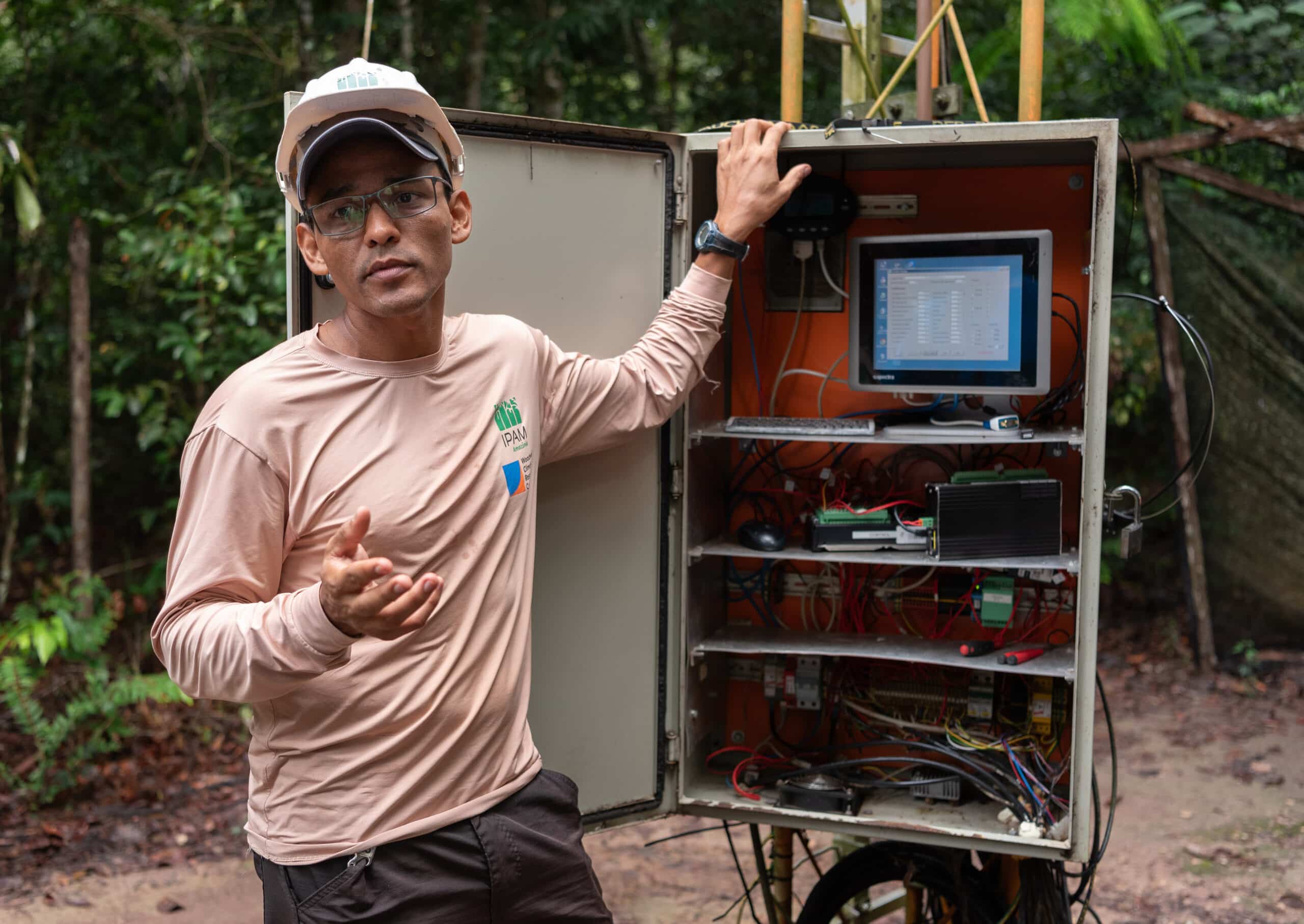 leo maracahipes-santos stands in front of the mechansim that controls the carbon tower and gestures towards the camera