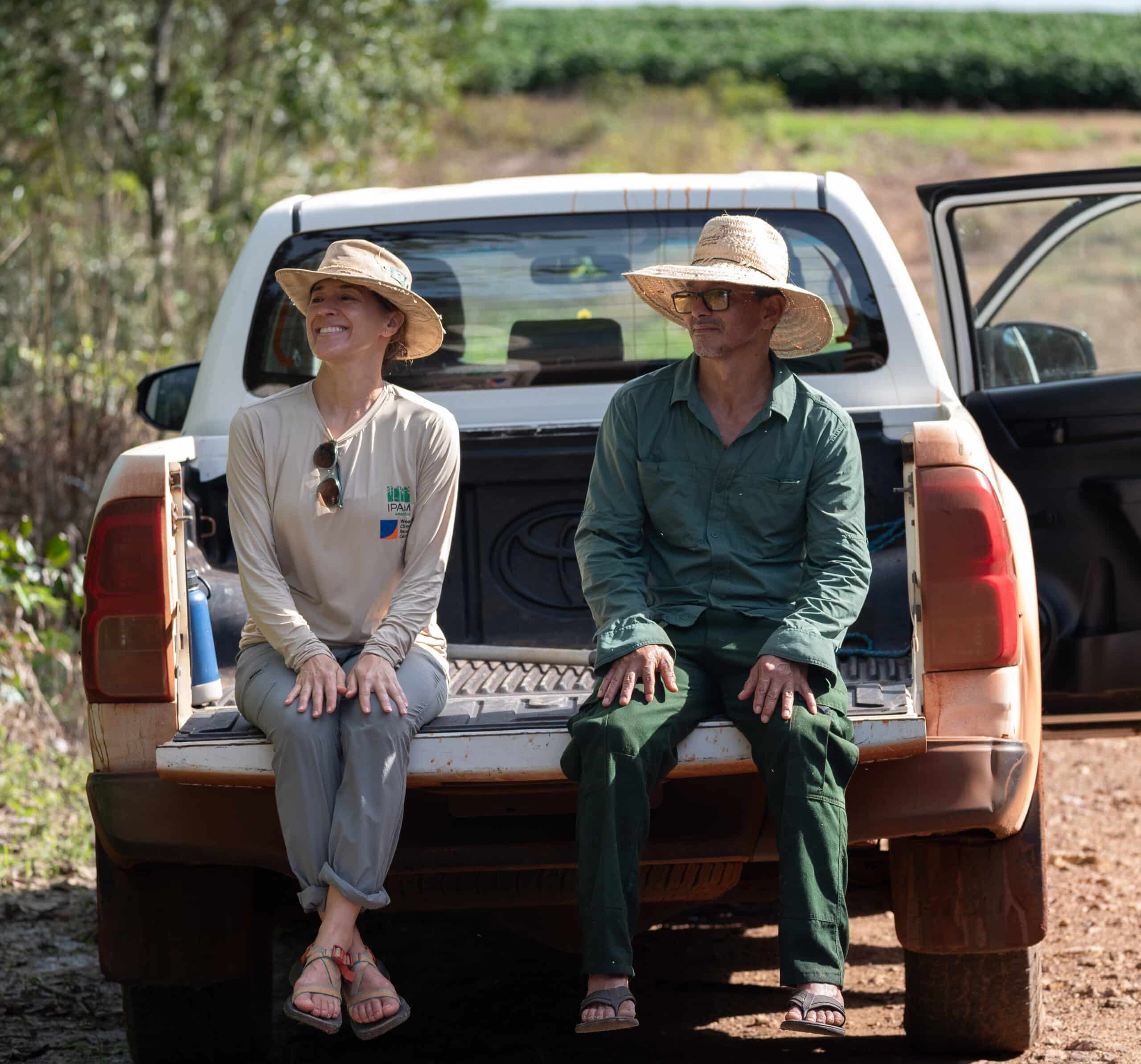 marcia macedo and santarem sitting in the back of a truck talking