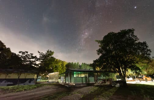 night sky with stars and milky way over green shed and buildings of research station