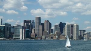 the Boston skyline as viewed from the water, with a sailboat in the foreground