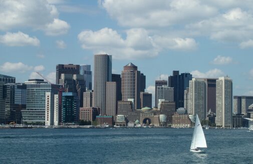 the Boston skyline as viewed from the water, with a sailboat in the foreground