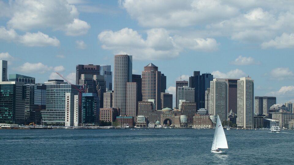 the Boston skyline as viewed from the water, with a sailboat in the foreground