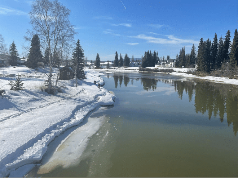 a large creek with snowy banks