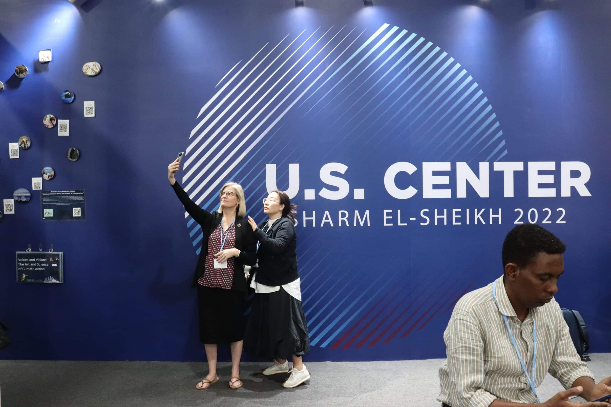 visitors at the Cop27 in egypt pose in front of the US center pavilion