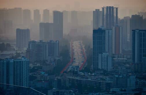 a city skyline of high-rise buildings darkened by smog